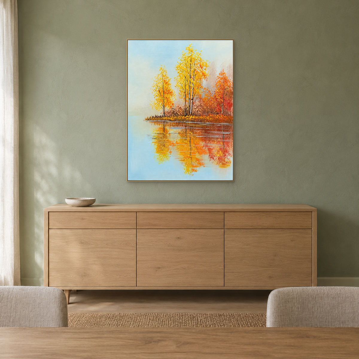 Paysage de lac automnal doré dans un cadre champagne, au-dessus d’un buffet en bois clair sur un mur vert doux