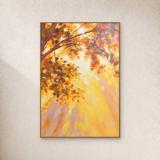 Tableau vertical de feuilles automnales ambrées et de lumière dorée, dans un fin cadre flottant doré sur un mur ivoire.