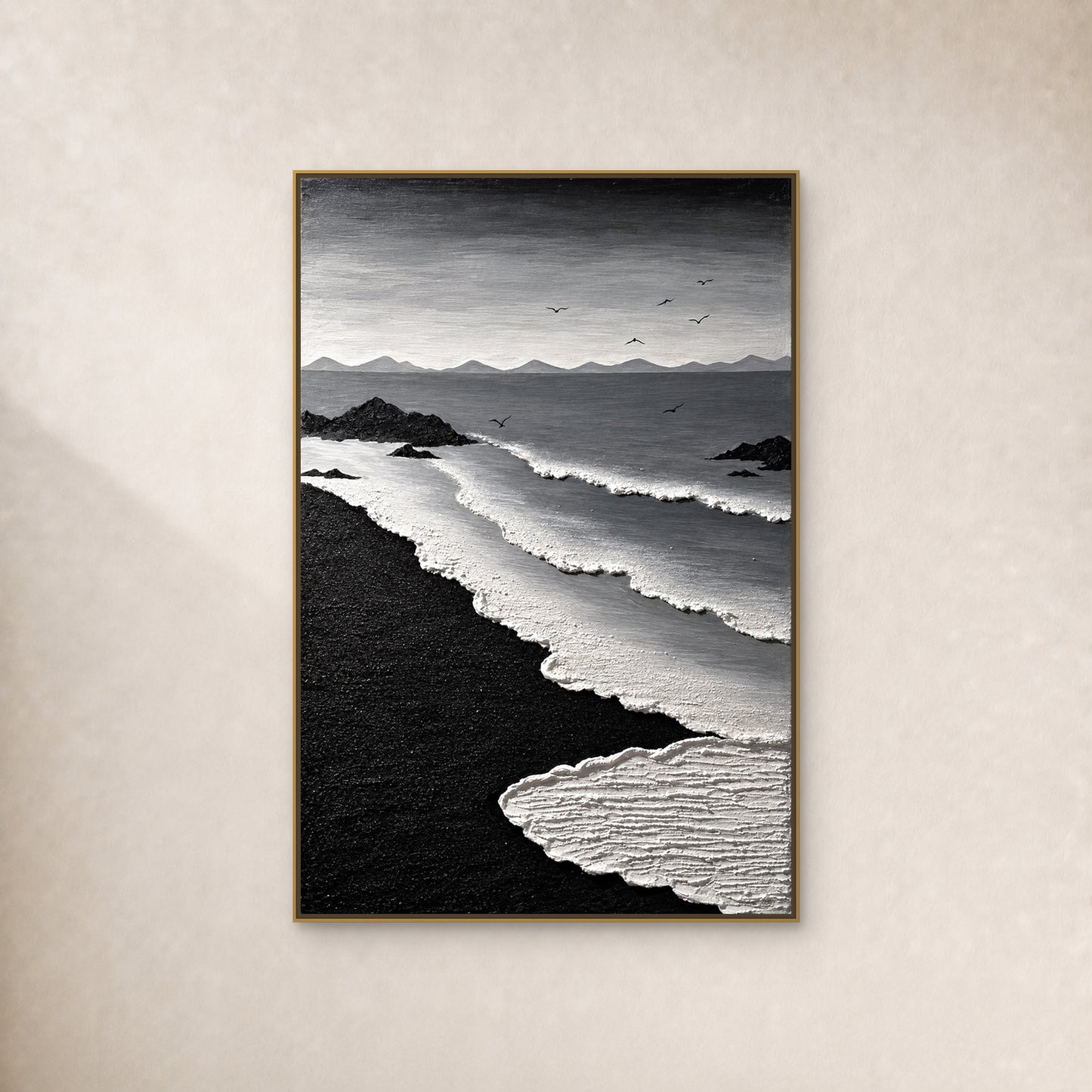 Tableau côtier noir et blanc, avec courbes d’écume, sable noir et sept oiseaux, dans un fin cadre flottant doré sur un mur ivoire chaud