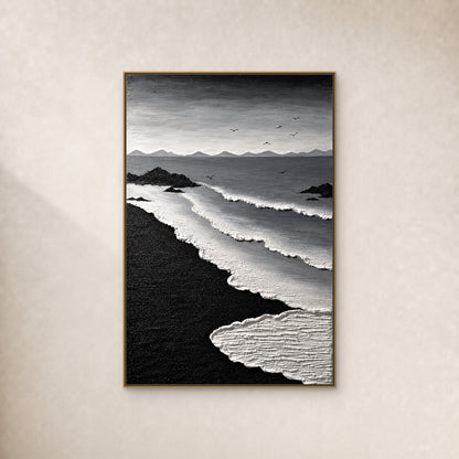 Tableau côtier noir et blanc, avec courbes d’écume, sable noir et sept oiseaux, dans un fin cadre flottant doré sur un mur ivoire chaud