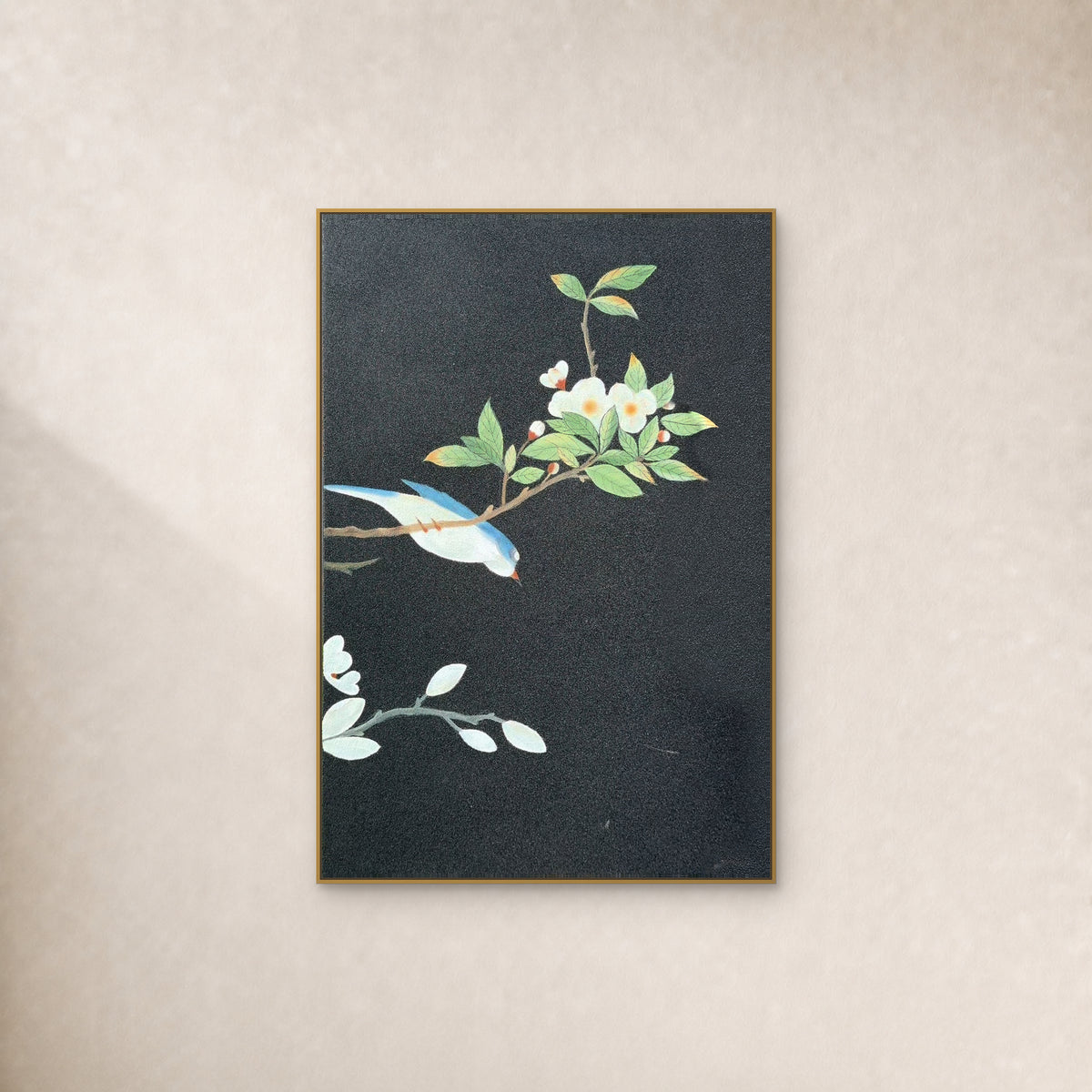 Oiseau bleu et ivoire et fleurs blanches sur fond anthracite, dans un cadre fin doré sur un mur ivoire