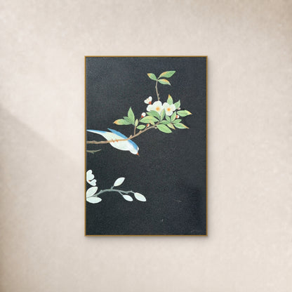 Oiseau bleu et ivoire et fleurs blanches sur fond anthracite, dans un cadre fin doré sur un mur ivoire