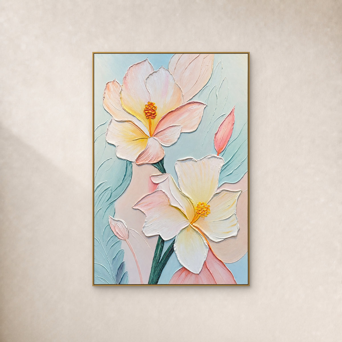 Two cream and blush flowers with raised yellow centres on pale aqua, in a thin gold frame against an ivory wall