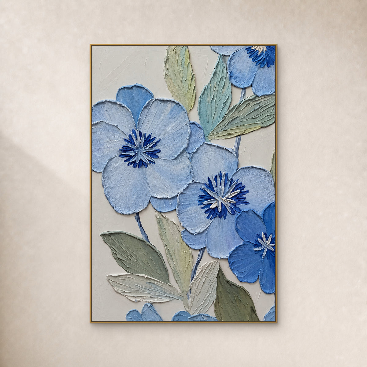 Fleurs bleu poudré aux cœurs cobalt et feuilles sauge, dans un cadre flottant fin doré sur un mur ivoire