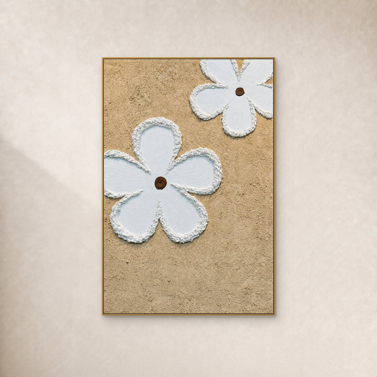 Deux grandes fleurs blanches à cœurs bruns sur fond beige, dans un fin cadre doré sur un mur ivoire