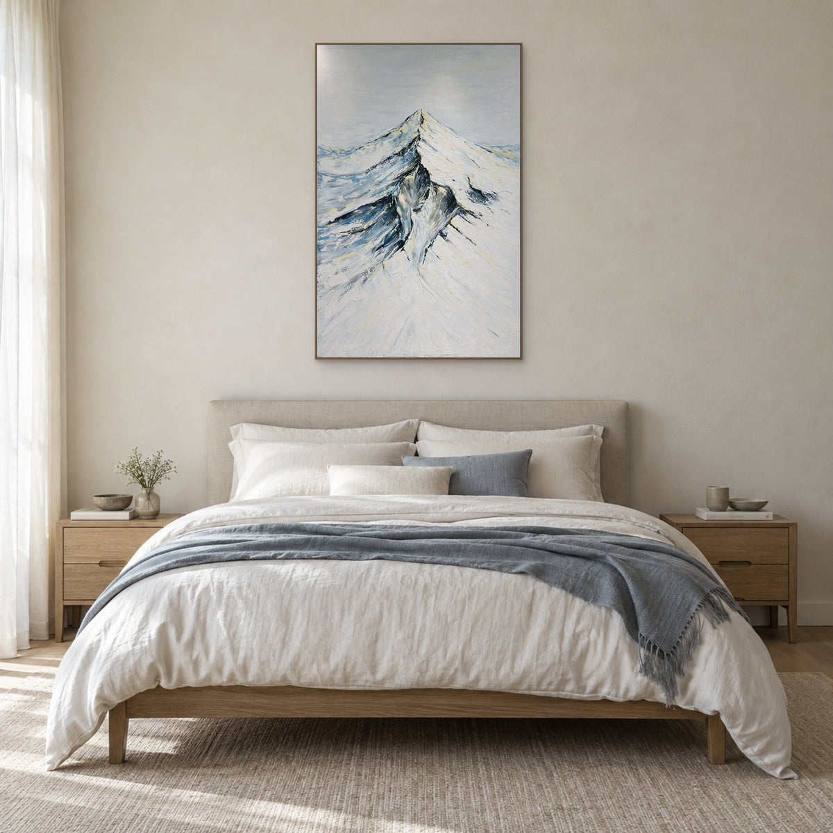Tableau vertical de montagne enneigée dans un cadre ton chêne, centré au-dessus d'un lit en lin