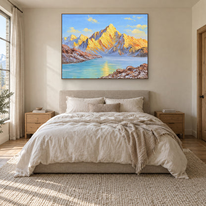 Blue lake and golden mountain painting in an oak-tone frame centred above a cream upholstered bed