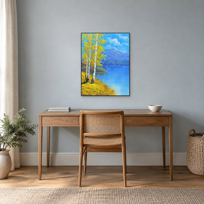 Bouleaux d’automne et lac bleu dégagé dans un fin cadre noir au-dessus d’un bureau en bois.