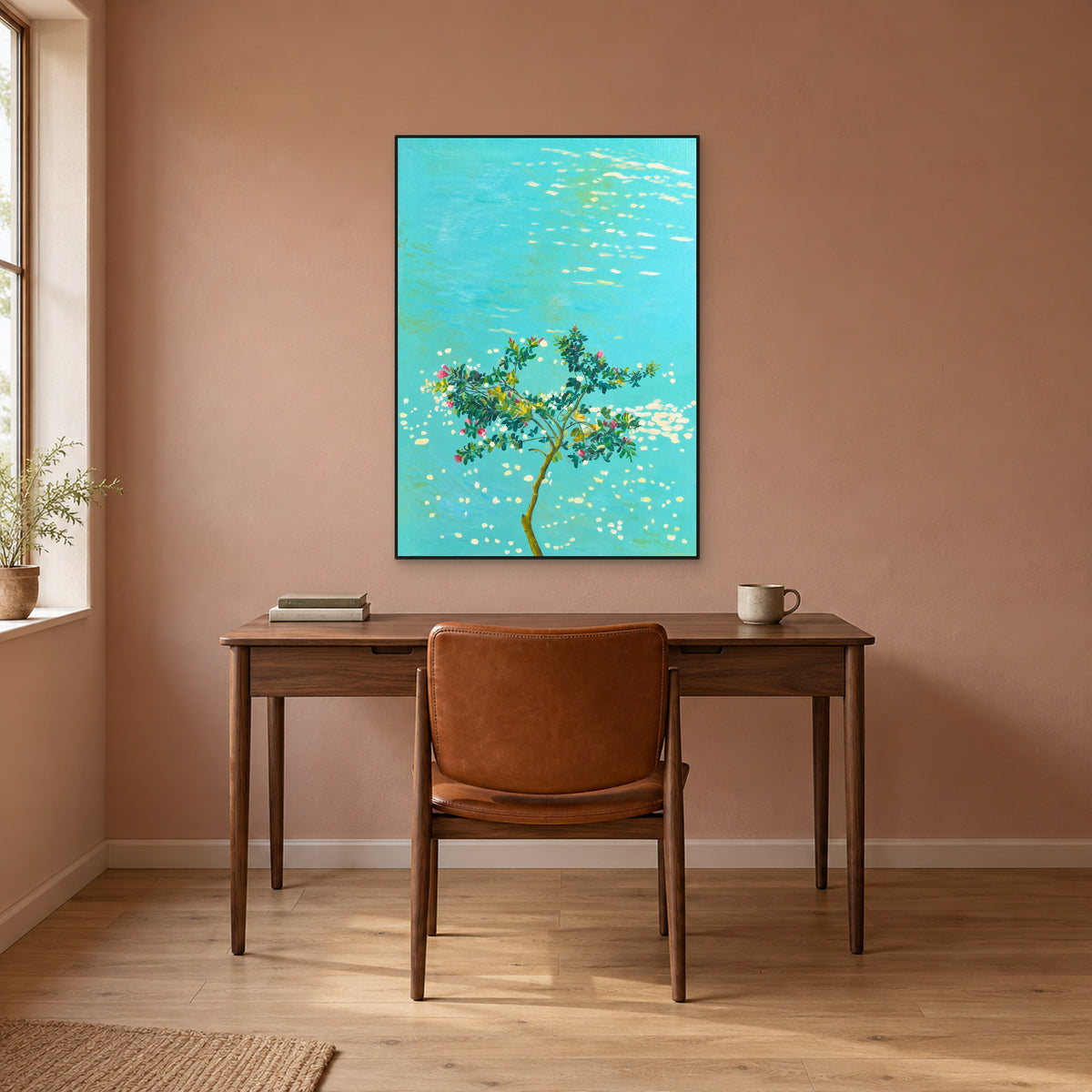 Flowering tree painting in a thin black floating frame above a walnut-tone desk against a warm terracotta wall