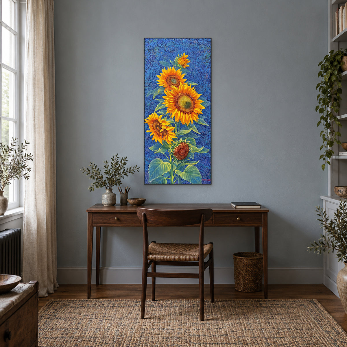 Tableau de tournesols bleu et jaune dans un cadre noir, au-dessus d’un bureau en bois sombre sur un mur gris bleu