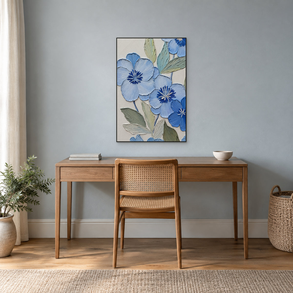 Fleurs bleues et feuilles sauge dans un cadre noir fin, au-dessus d'un bureau en bois sur un mur bleu-gris