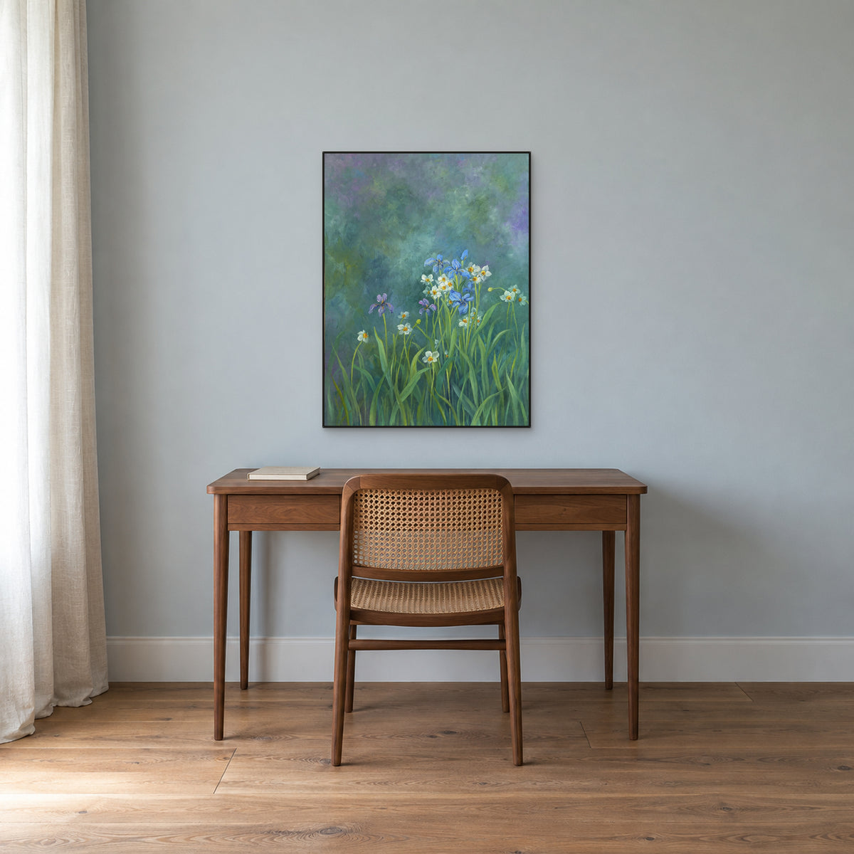 Iris bleus et fleurs blanches dans un fin cadre noir au-dessus d’un bureau en noyer, sur un mur bleu-gris