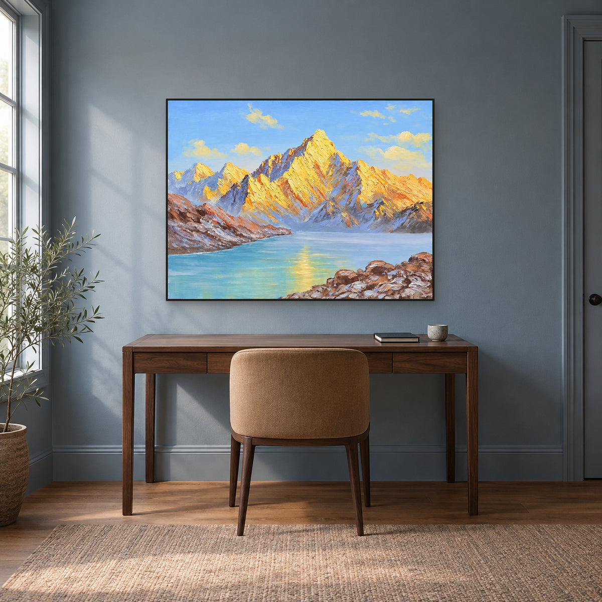 Golden peaks and turquoise lake in a slim black frame above a walnut-coloured desk against a blue-grey wall