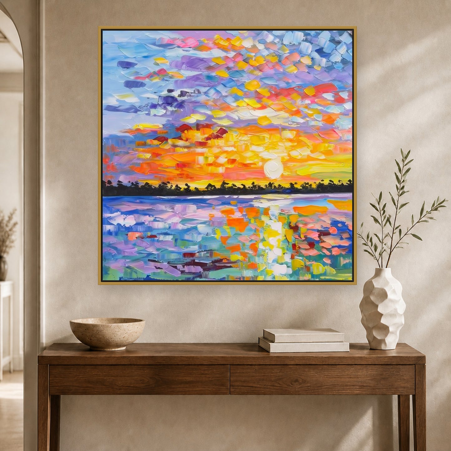Colorful square sunset painting in a slim brass floating frame above a warm wood console