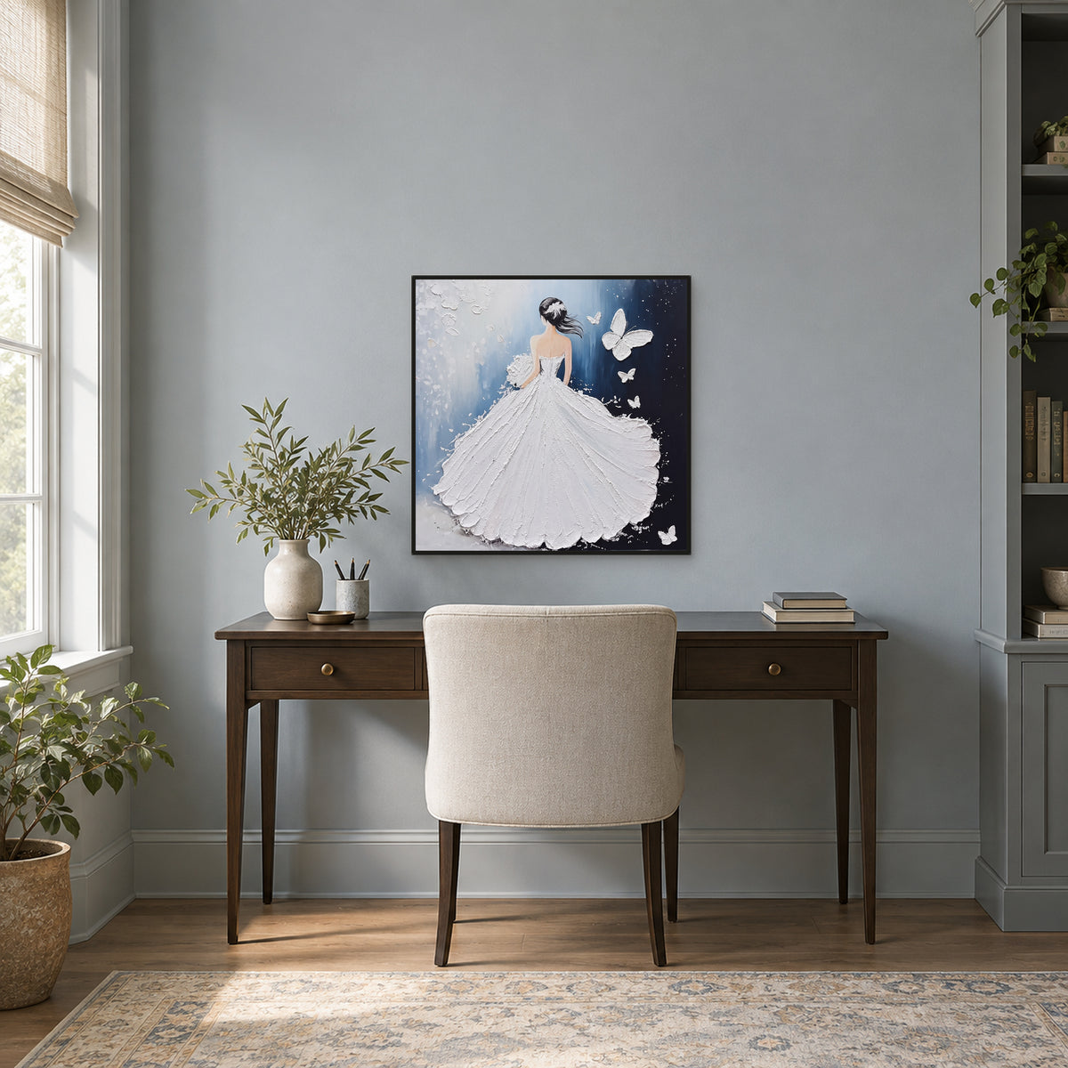 Tableau figuratif bleu et blanc dans un cadre noir fin, au-dessus d’un bureau en bois sur un mur gris bleuté