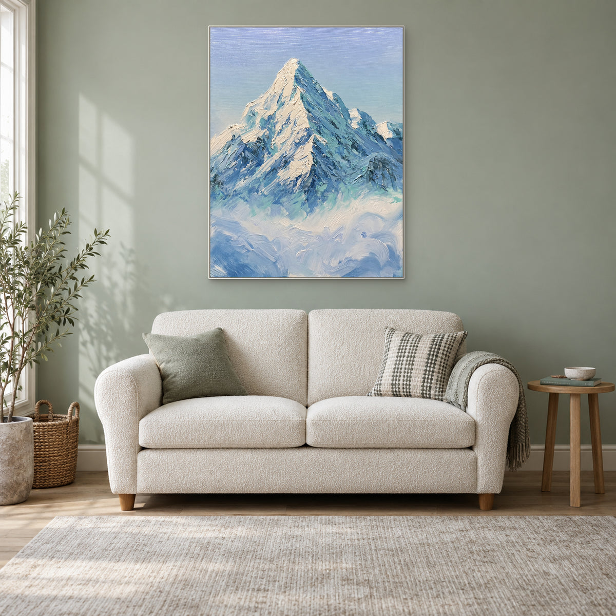 Vertical snowy mountain artwork in a white frame, above a cream loveseat in a sage reading nook.