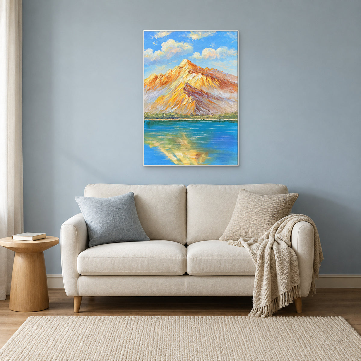 Tableau de montagnes et de leur reflet dans un cadre blanc, au-dessus d'un petit canapé crème sur un mur bleu doux