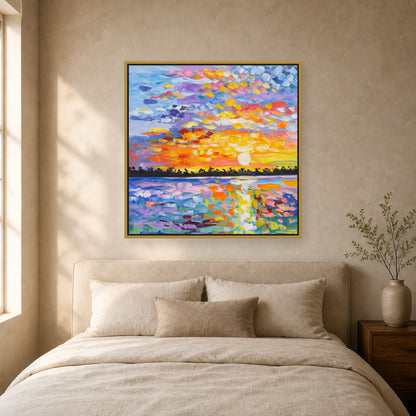 Colorful square sunset painting in a slim brass floating frame above a neutral upholstered bed