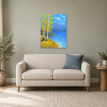 Paysage de bouleaux et de lac dans un cadre blanc au-dessus d’un petit canapé crème, avec coussin bleu et plantes.
