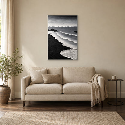 Écume blanche texturée et sable noir dans un cadre flottant blanc, au-dessus d’un petit canapé beige près d’une fenêtre et d’une table noire
