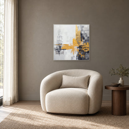 Tableau abstrait carré aux touches dorées dans un cadre blanc, au-dessus d’un fauteuil ivoire sur un mur taupe