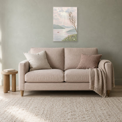 Pastel landscape in a white floating frame above a blush linen loveseat