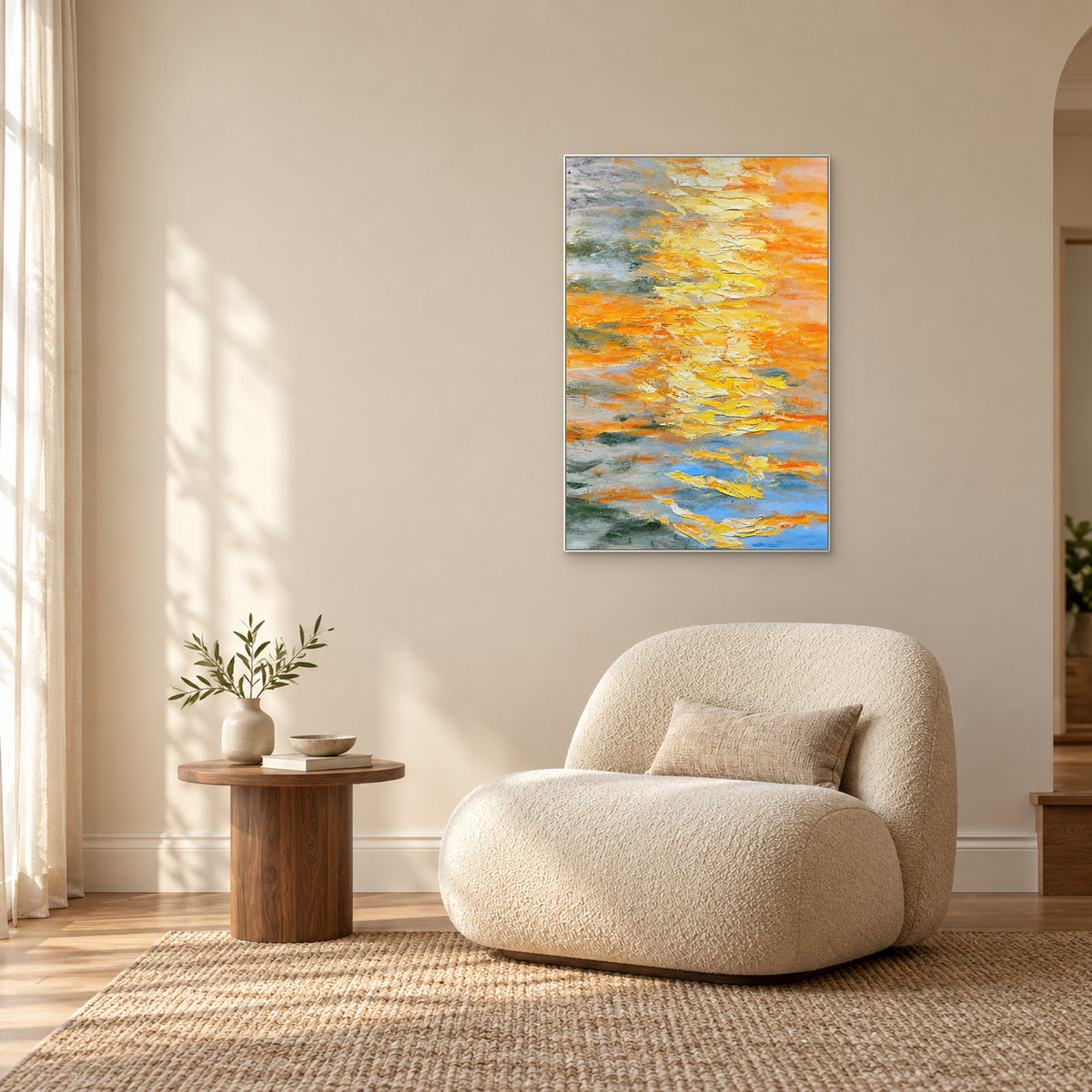 Saffron Layers in a white frame above a rounded cream reading chair, beside a small walnut table and sunlit window