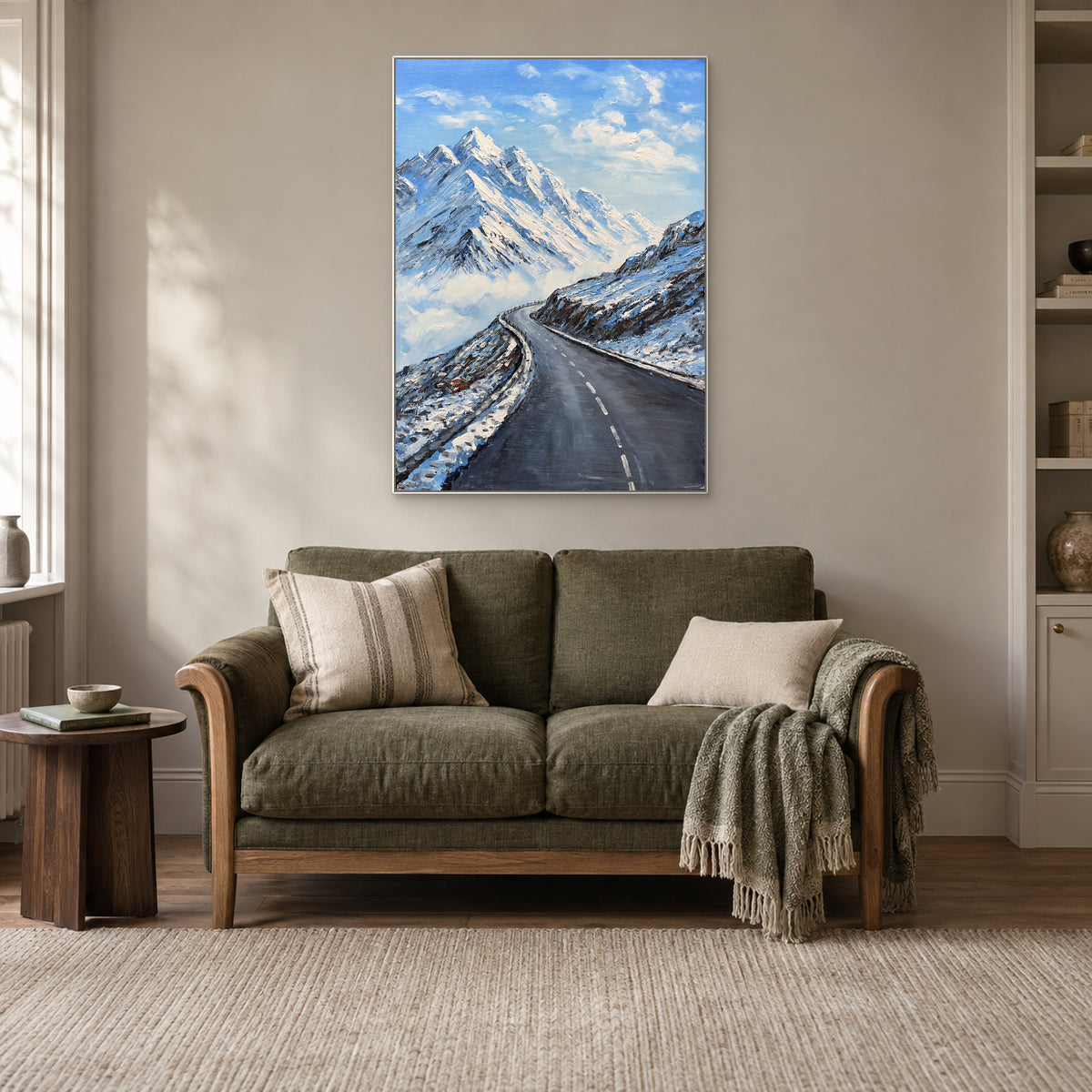Paysage de montagne bleu et blanc dans un cadre flottant blanc, au-dessus d’un canapé de lecture vert olive