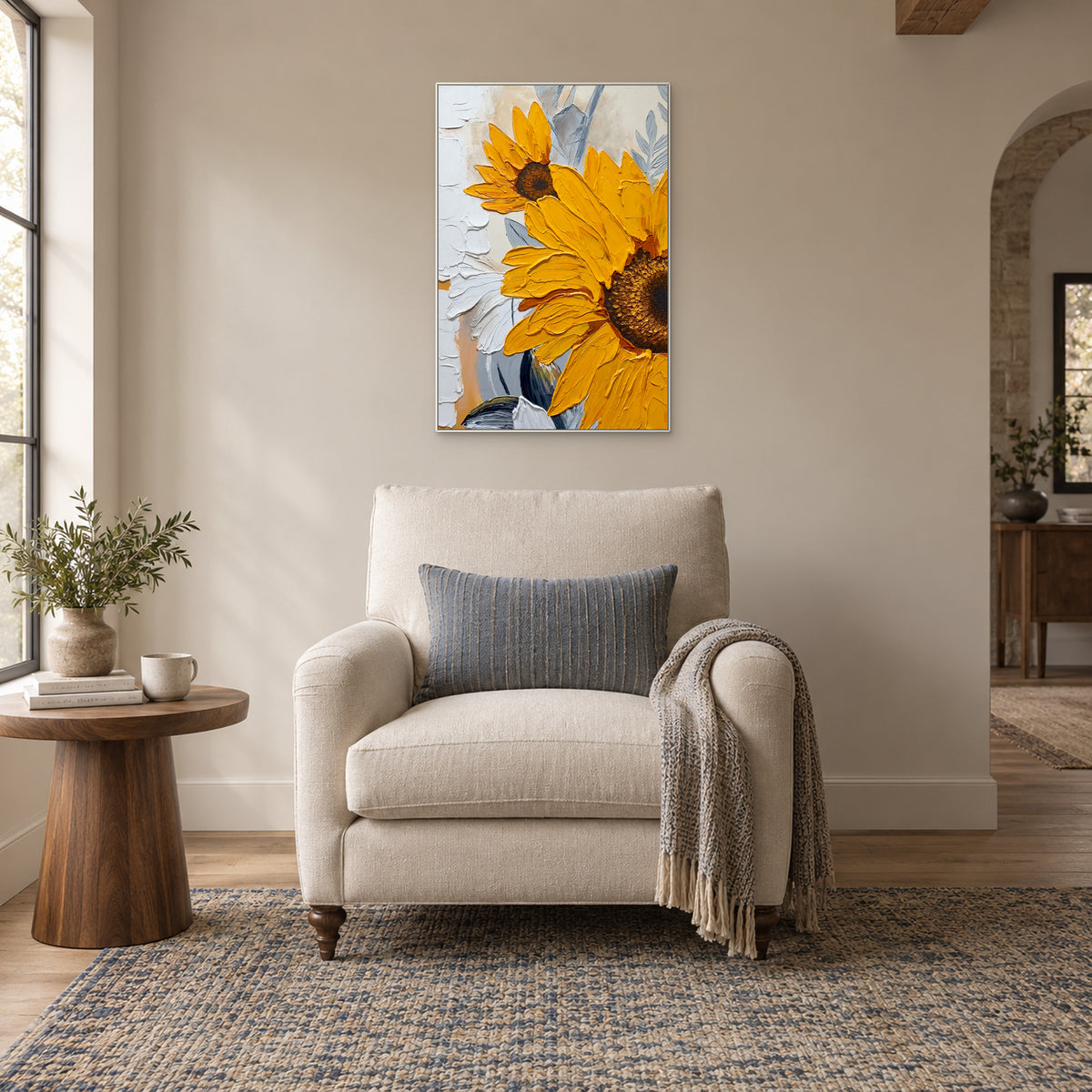 White-framed sunflower painting above a cream reading chair with a blue cushion beside a window