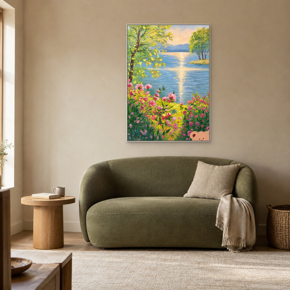 Vertical lake and pink flower painting in a white floating frame above a curved moss-green loveseat beside a window