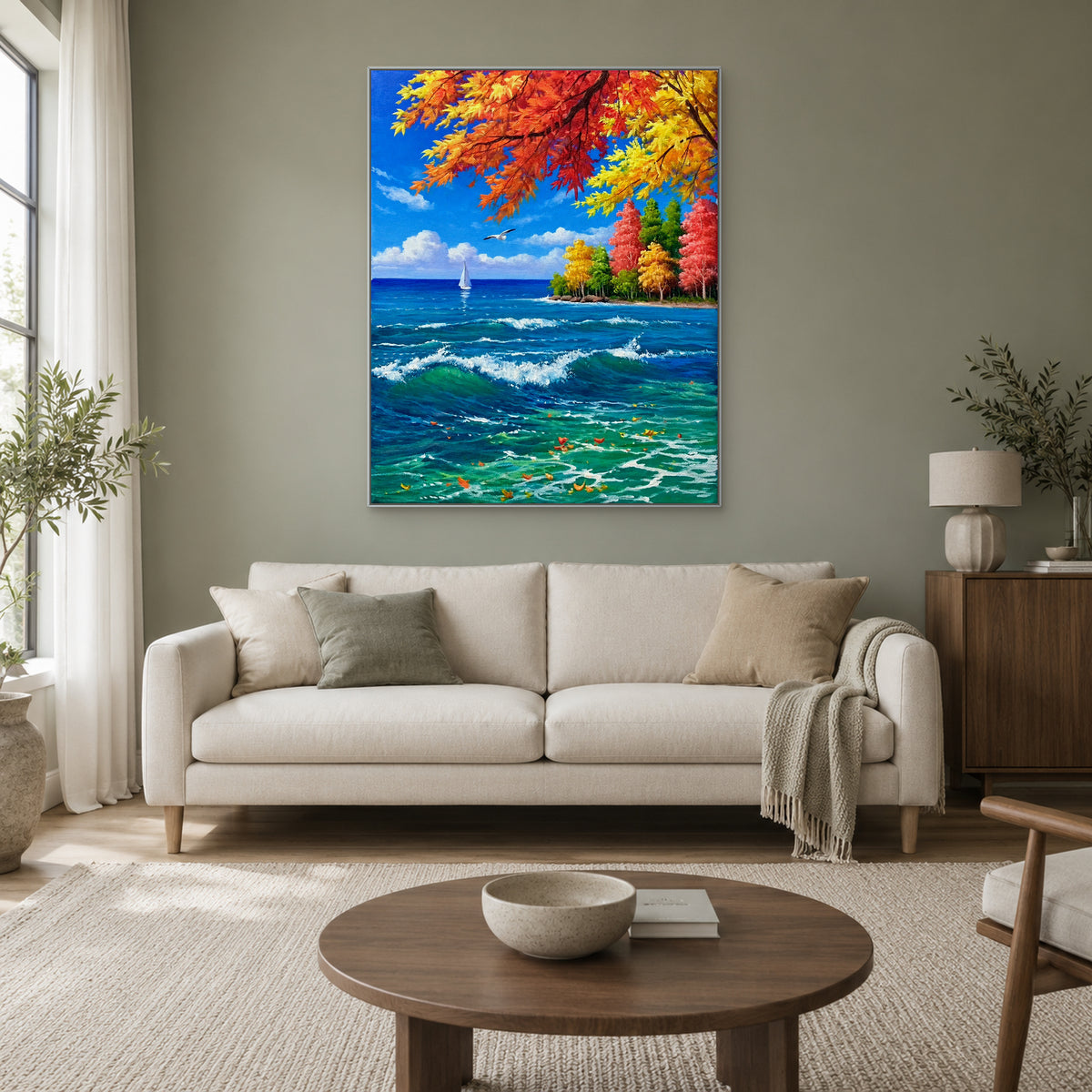 Feuilles d’automne colorées et vagues dans un cadre argenté, au-dessus d’un canapé crème sur un mur sauge