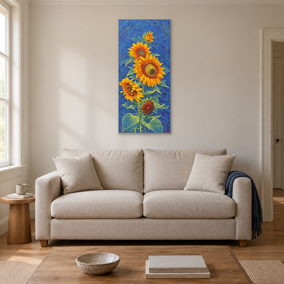 Tableau de tournesols sur fond cobalt dans un cadre argenté, centré au-dessus d’un canapé clair