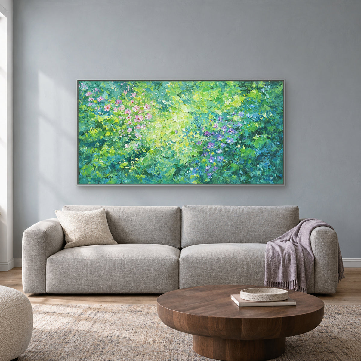 Tableau floral vert horizontal dans un cadre flottant argenté, au-dessus d’un canapé gris clair devant un mur bleu grisé