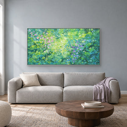 Tableau floral vert horizontal dans un cadre flottant argenté, au-dessus d’un canapé gris clair devant un mur bleu grisé