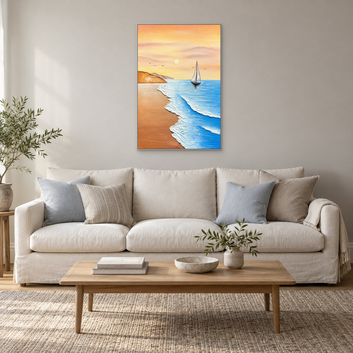 Peach and blue seascape in a silver-tone frame centred above an ivory sofa with blue cushions