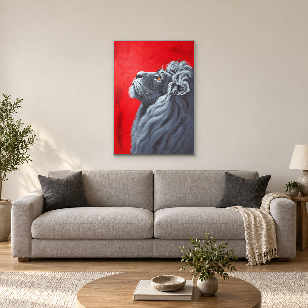 Tableau de lion dans un cadre argenté, centré au-dessus d’un canapé gris clair contre un mur ivoire