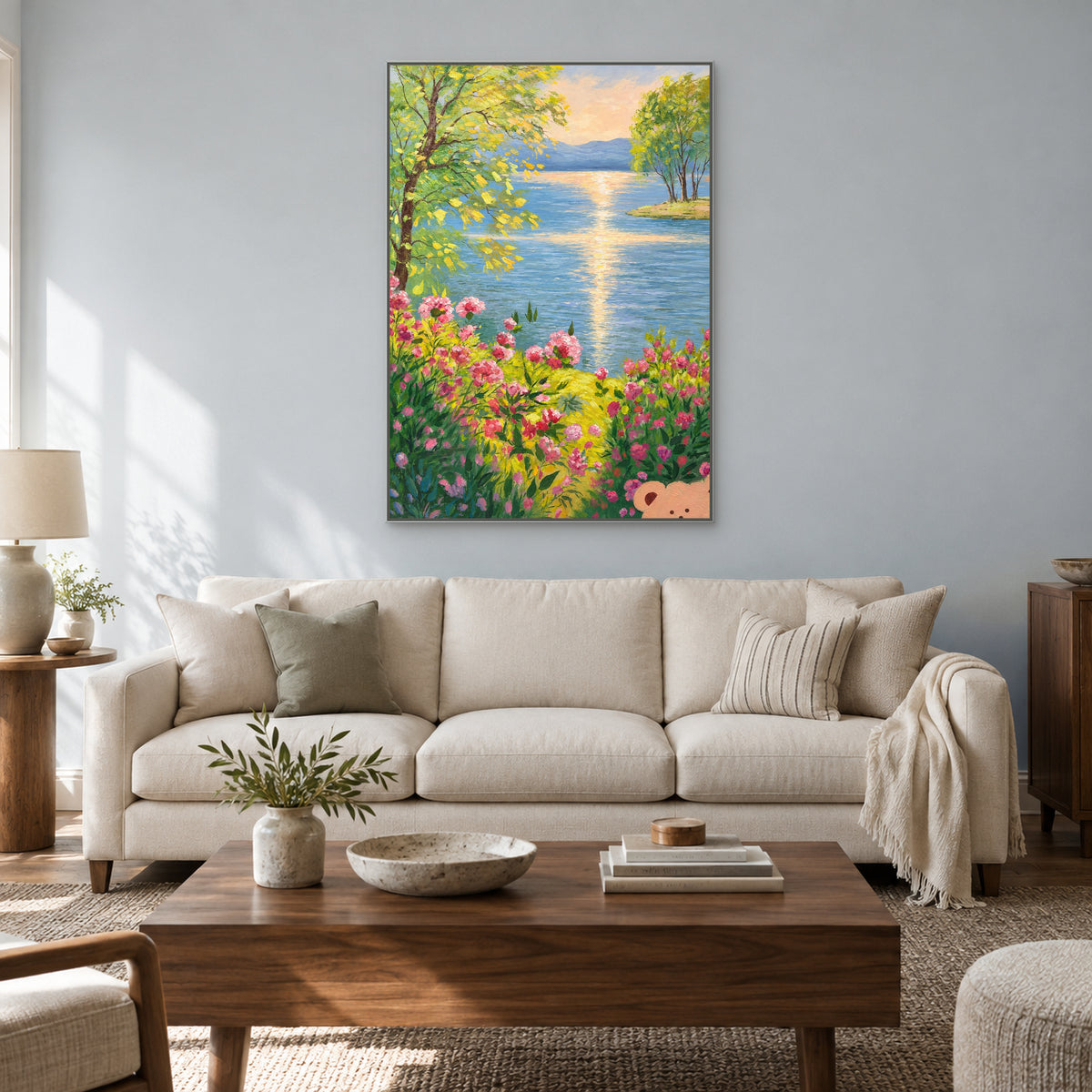 Blue lake and golden reflection painting in a silver-toned floating frame above a pale sofa and wood coffee table