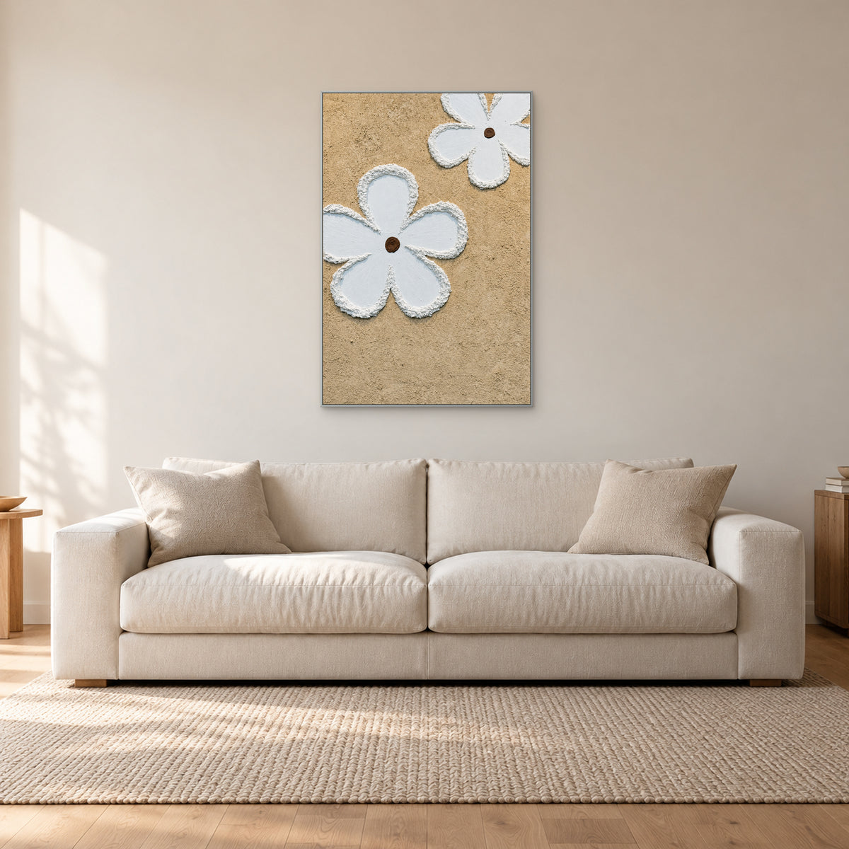 Tableau vertical de fleurs blanches en relief à fin cadre argenté, au-dessus d’un canapé blanc cassé