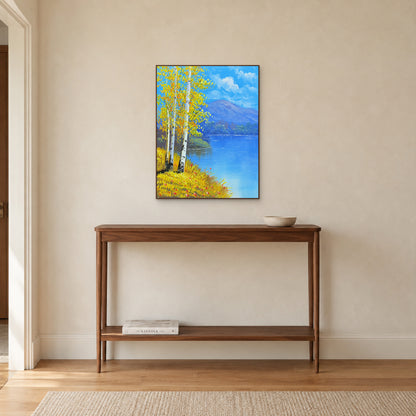 Tableau de rive bordée de bouleaux dans un cadre ton noyer au-dessus d’une console étroite en bois.