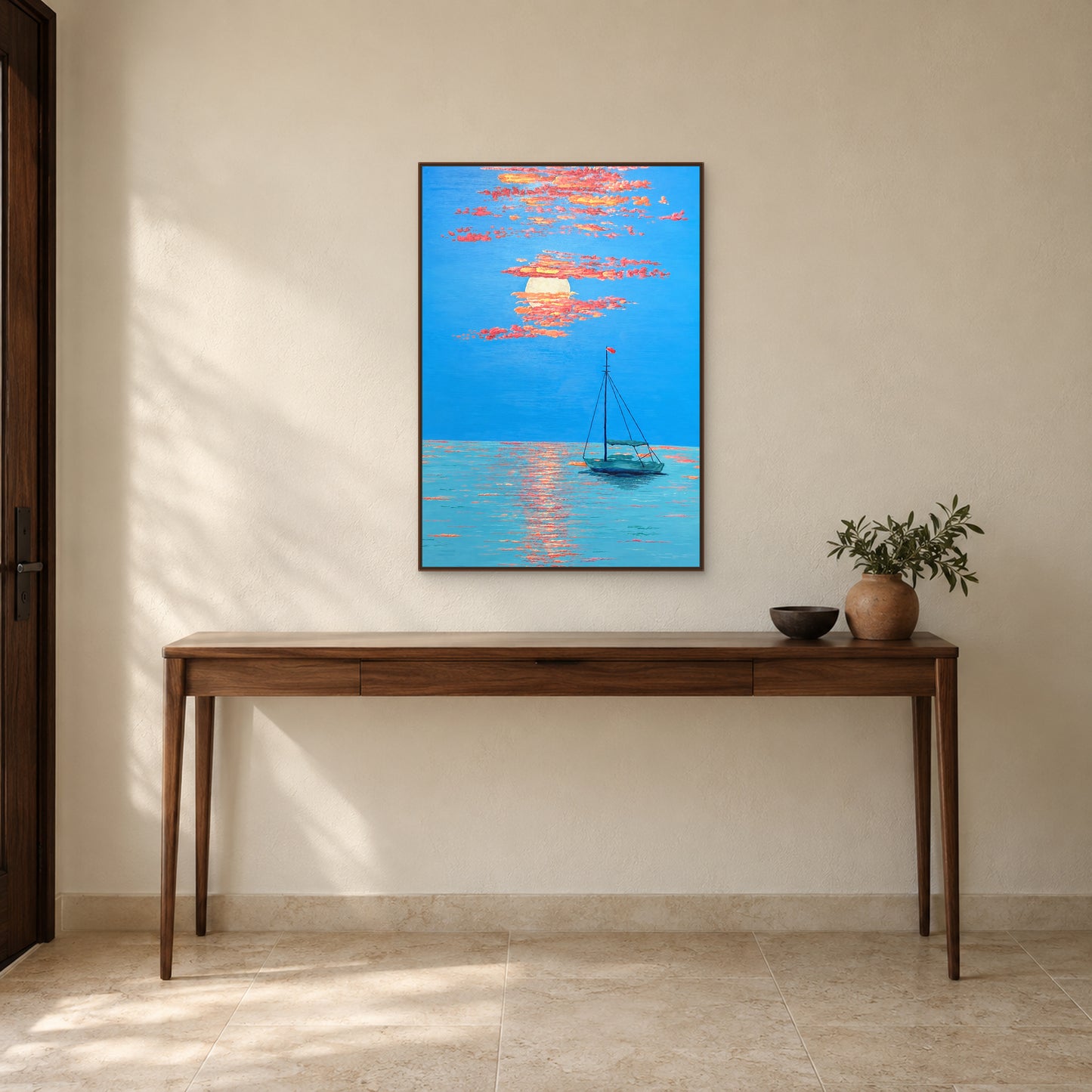 Tableau bleu et corail d’une barque au couchant, cadre flottant ton noyer, au-dessus d’une fine console d’entrée en bois.