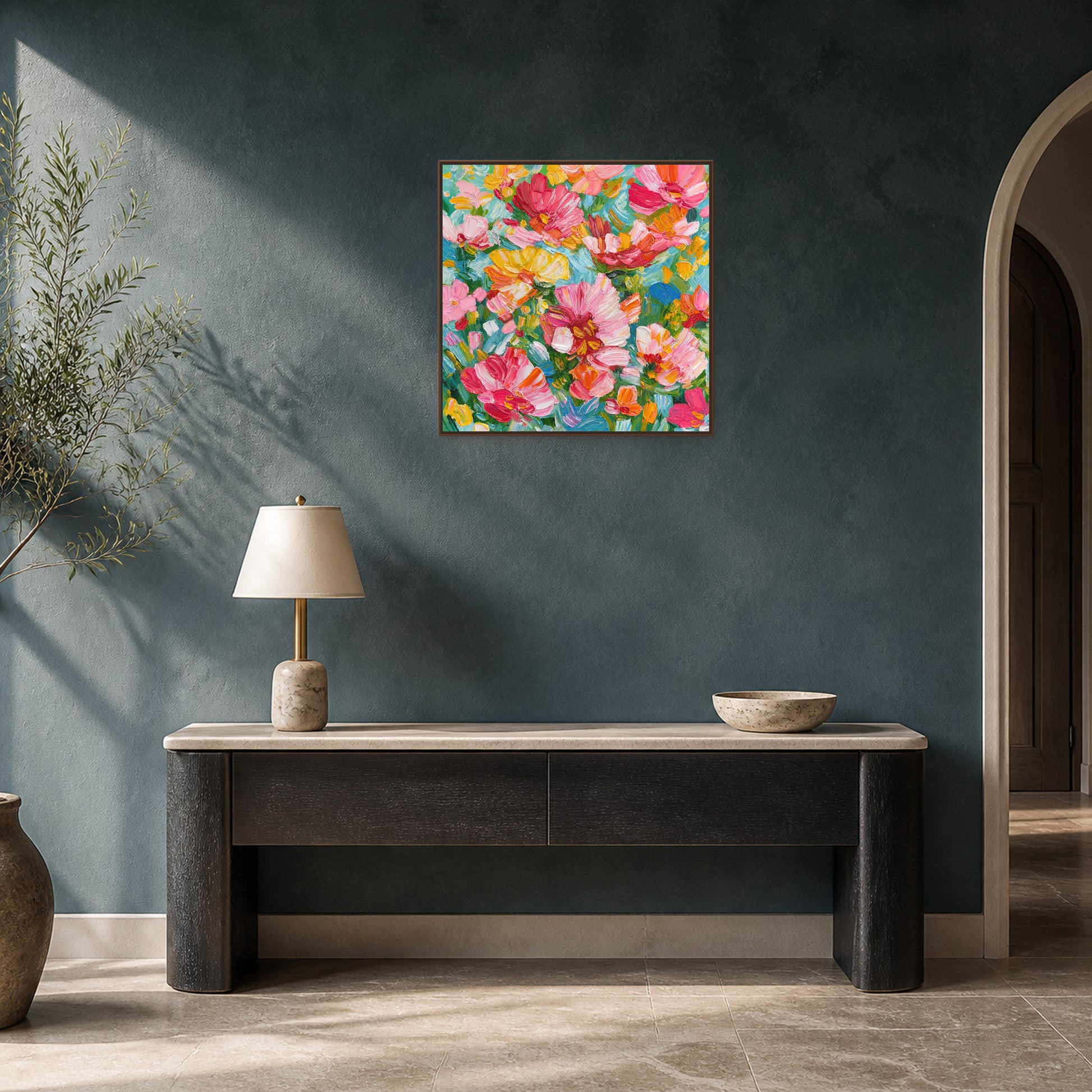 Abondance florale dans un fin cadre flottant en noyer au-dessus d’une console en chêne foncé sur un mur d’entrée bleu-vert profond