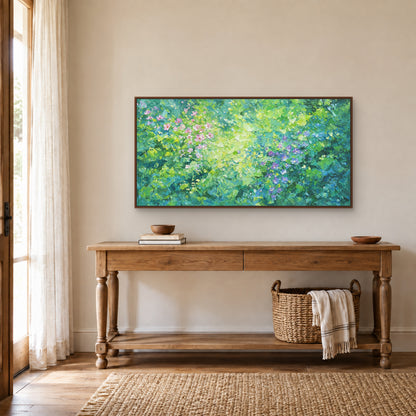 Panorama vert fleuri dans un cadre flottant ton noyer, au-dessus d’une console en bois à pieds tournés et d’un panier
