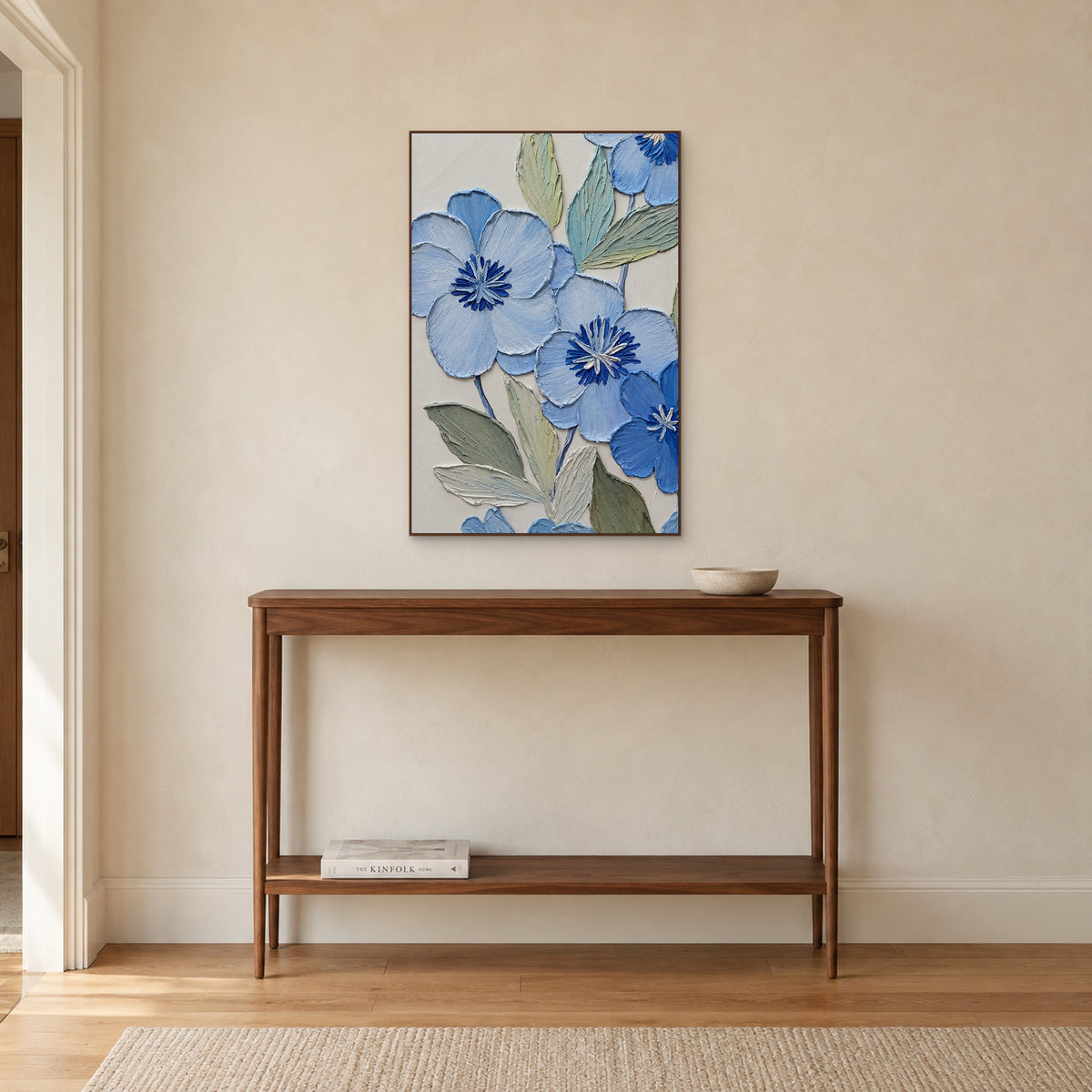 Tableau vertical de fleurs bleu poudré dans un cadre ton noyer, au-dessus d'une console d'entrée en bois