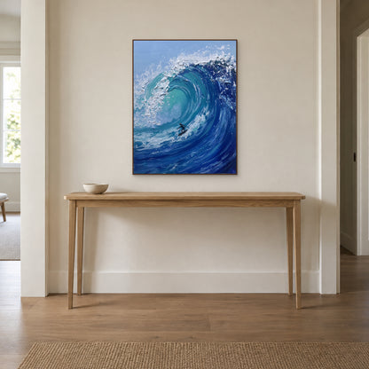Tableau de surfeur dans un cadre ton noyer, centré au-dessus d’une console en bois dans une entrée