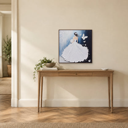 Robe blanche et papillons dans un cadre ton bois foncé, au-dessus d’une console étroite sur un mur d’entrée ivoire