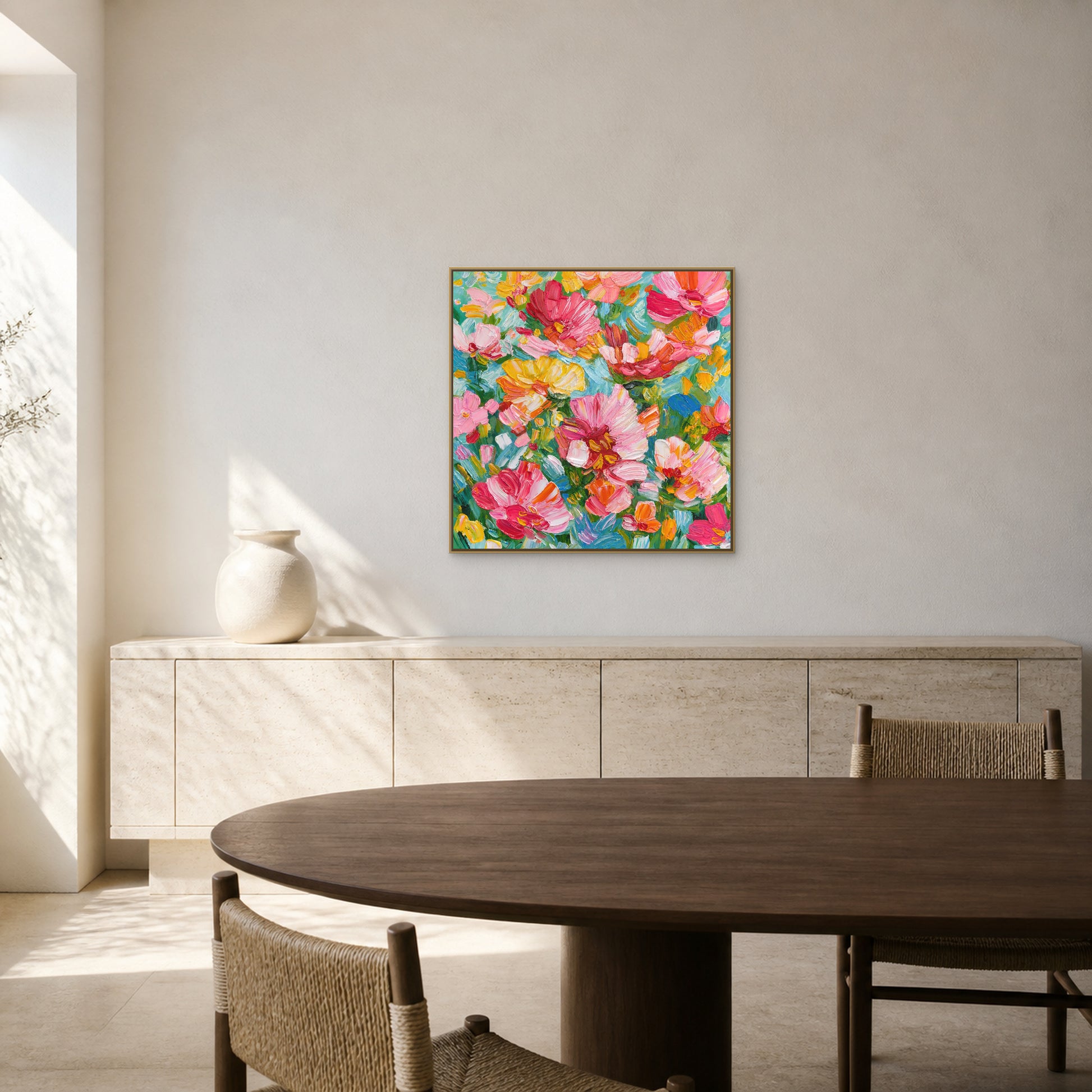 Abondance florale dans un fin cadre flottant champagne au-dessus d’un buffet bas en travertin clair dans une salle à manger lumineuse