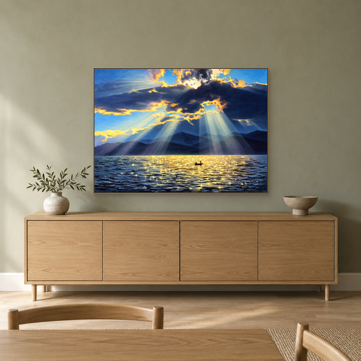 Tableau de lac bleu et or dans un cadre champagne, au-dessus d'un buffet en bois sur un mur vert sauge