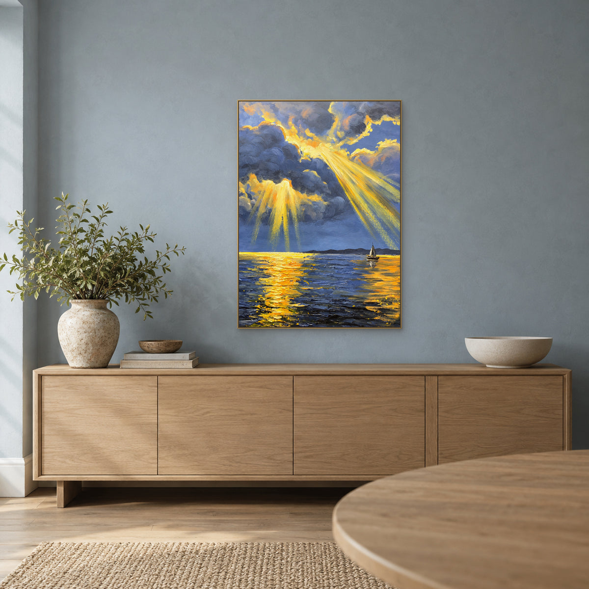 Marine bleu-gris aux reflets dorés, dans un cadre champagne au-dessus d’un buffet en chêne, sur un mur bleu.