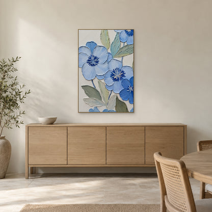 Fleurs bleues et feuillage sauge dans un cadre ton champagne au-dessus d'un buffet de salle à manger en bois clair