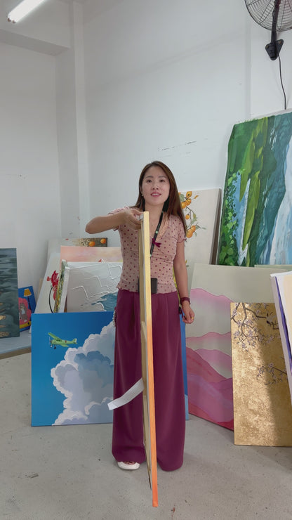 A person turns a narrow orange sailboat painting to show its front, followed by a framed wall display